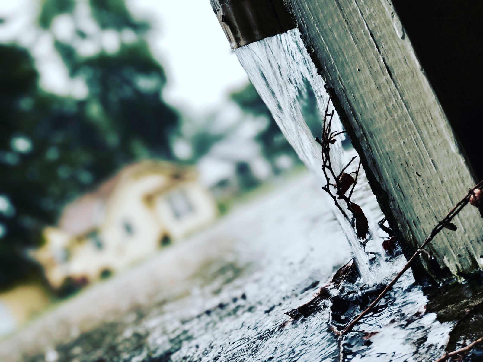 Rainwater streaming steadily out of a downspout during rain