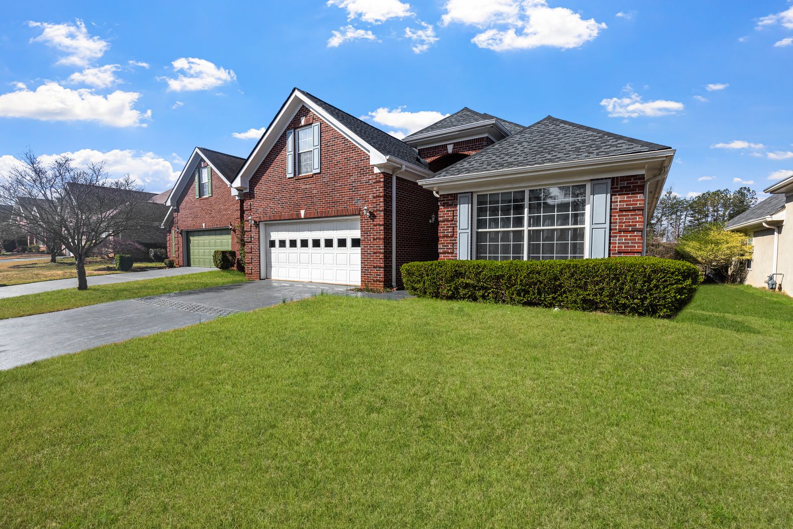 Red brick home with white gutters, a green lawn, and blue sky